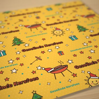 Braai Kersfees wrapping paper roll, 30 x 72 in: Angled close-up of a flat sheet on oak, matte paper grain, shallow depth of field