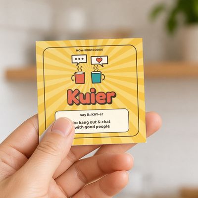 Kuier magnet (Sunshine): Hand holding the magnet in a bright kitchen (no face)