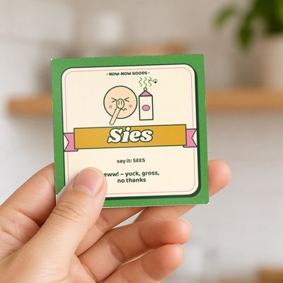 Sies magnet (Veld): Hand holding the magnet in a bright kitchen (no face)